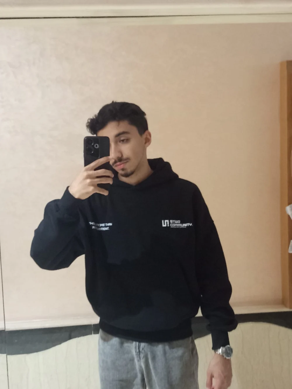 Aymane in a black hoodie taking a mirror selfie